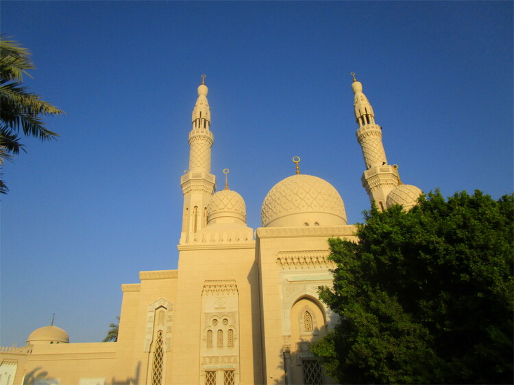 A sandstone-coloured mosque with two minarets against a dark blue sky