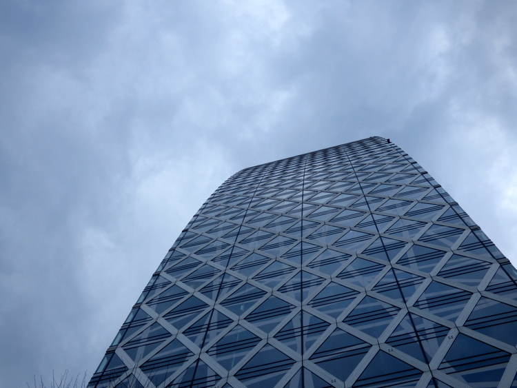 A view up the glass facade of a skyscraper with a geometric diamond pattern on it