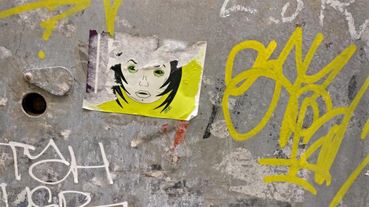 A half-ripped neon green sticker on a transformer box showing a confused cartoon face